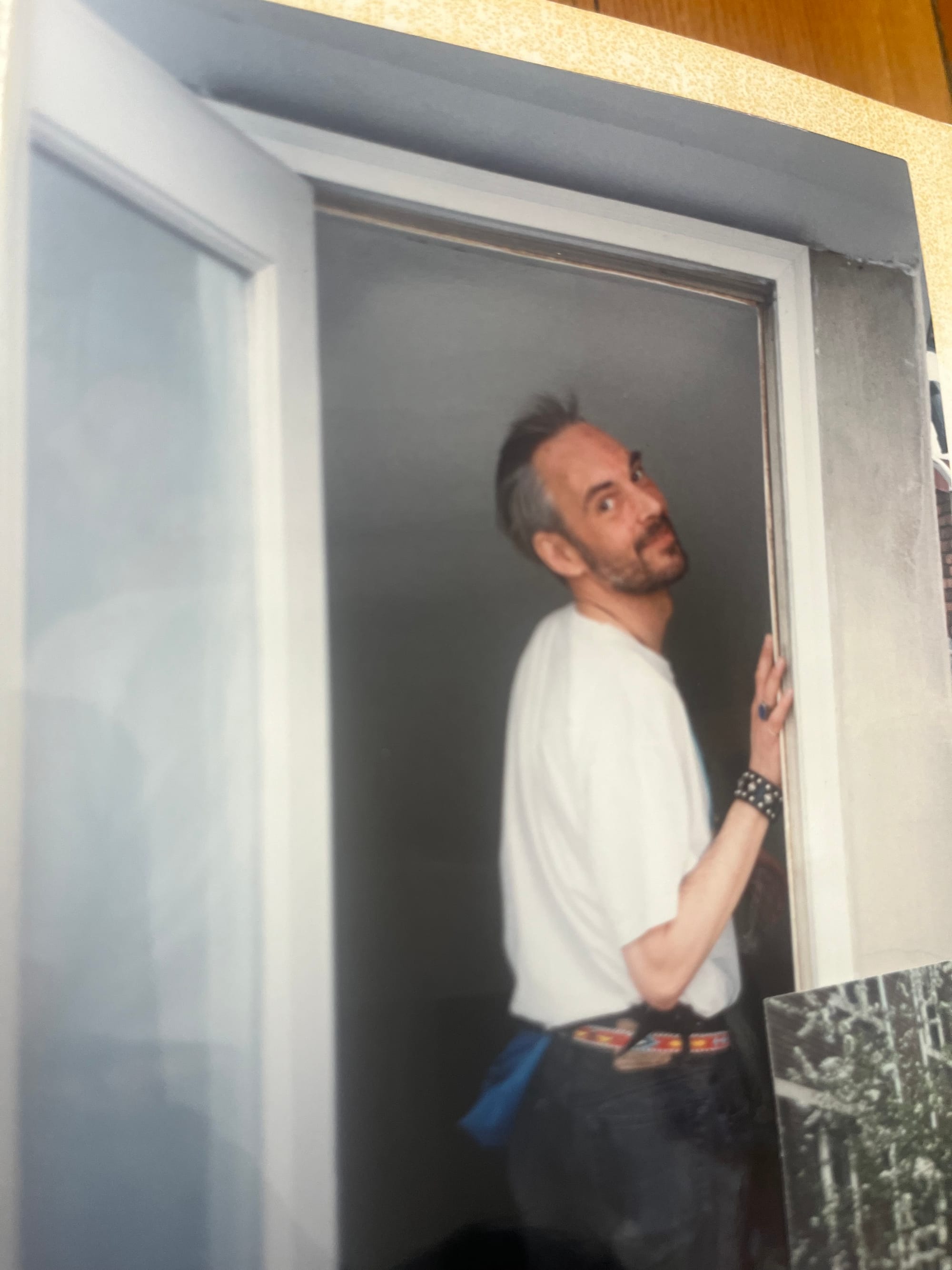 White man with greying brown hair and a beard paused in a doorway, looking fondly, a bit mischeviously at the camera.